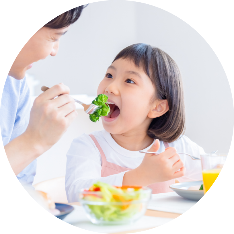 お母さんが子供に野菜を食べさせます